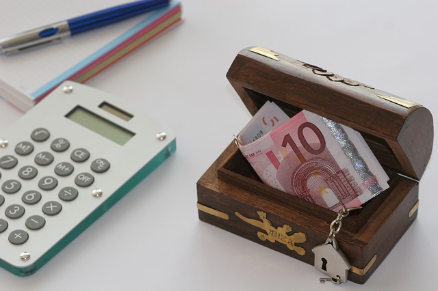 kalkulačka a malá truhlice s bankovkami